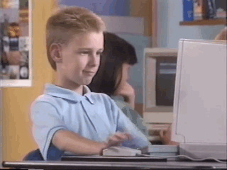 kid in front of a computer smiles and shows thumbs up
